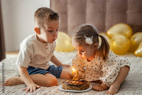 Brother and sister celebrating birthday and blowing candle on a cake.