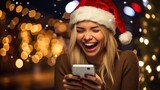 A happy girl in a Santa hat holds a smartphone in her hands