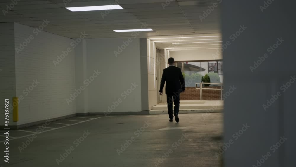 Businessman in a black suit walks in the car park. Slow motion Businessman in a black suit walks in the car park. Slow motion
