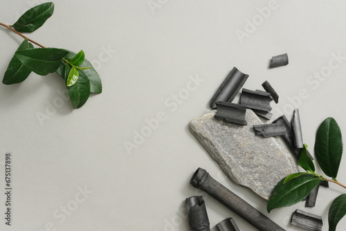 Fototapeta Naklejka Na Ścianę i Meble -  Green tea leaves and bamboo charcoal on gray background. Blank space for design and product advertising. Cosmetics extracted from bamboo charcoal and green tea are good for the skin.