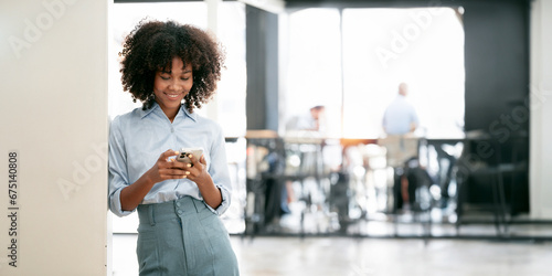 Foto Smiling african american businesswoman using smart phone leaning at office