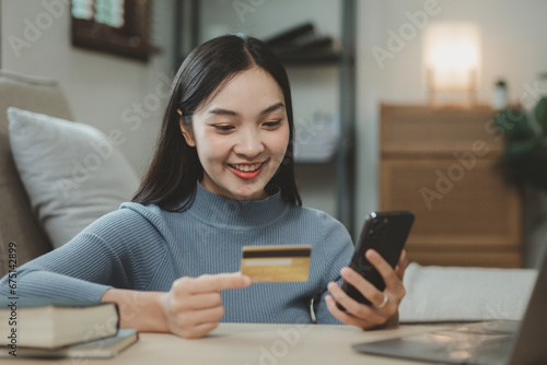 doing online shopping on the sofa in the living room, Use a credit card to make online payments while at home on day off, Use a laptop to enter a credit card information to pay for the service.