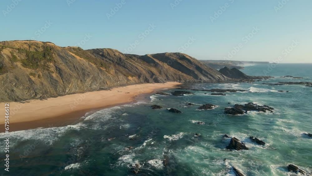 Aerial view of stunning beach with sunset light and waves crashing on the shore on the west coast of Portugal. Aerial view of stunning beach with sunset light and waves crashing on the shore on the west coast of Portugal.