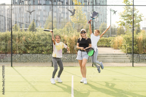 mother and children play paddle tennis