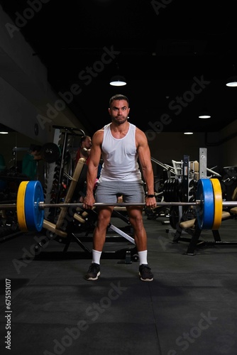 Strong Hispanic man deadlift at a gym.