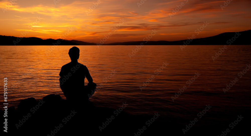 sylwetka mężczyzny medytującego na plaży przy zachodzie słońca - obrazy, fototapety, plakaty 