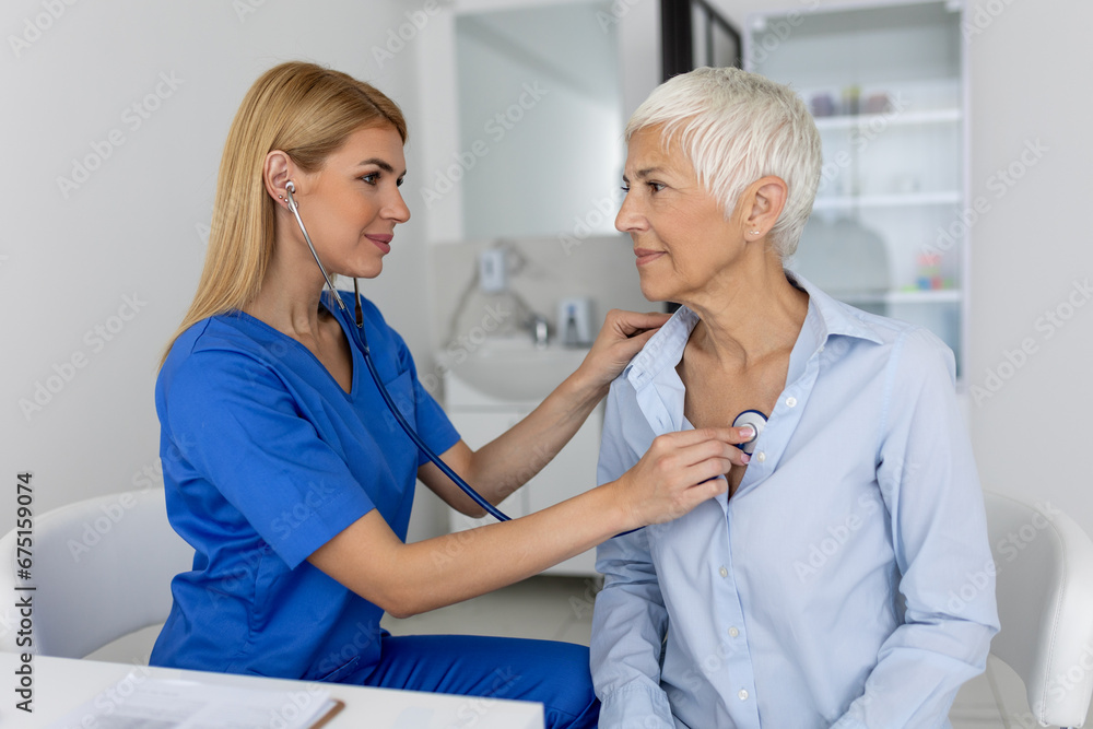 Fototapeta premium Young female doctor listen to senior patient heart chest with stethoscope at clinic meeting. Woman GP checkup examine woman client with phonendoscope. healthcare concept.