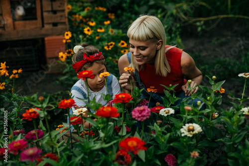 Mom and daughter happily smell flowers in their countryside garden
