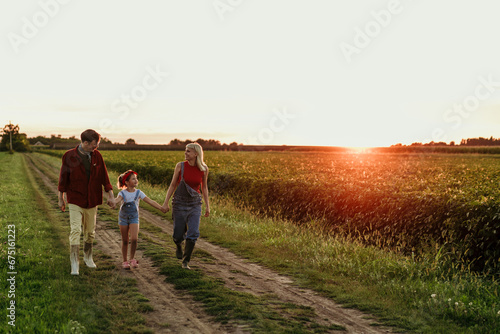 A content family of three shares a peaceful moment in the countryside, soaking in the beauty of the sunset after a busy day.