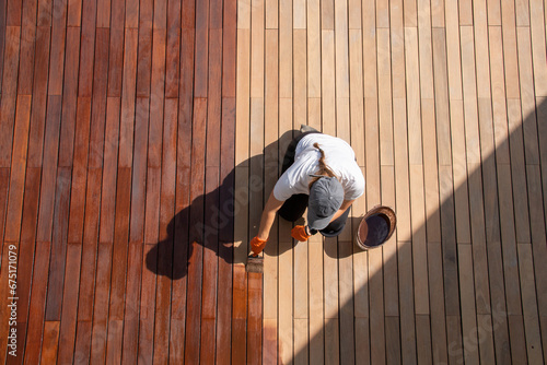 Workwoman staining wood deck boards outdoors, full body overhead view. Space for text
