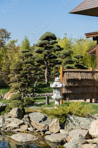 Japanese garden in Krasnodar Galitsky Park. Topiary art. Along shore of pond, between neatly trimmed trees and bushes, stands traditional Japanese stone lamp. Snow Lantern by Yukimi Toro. photo