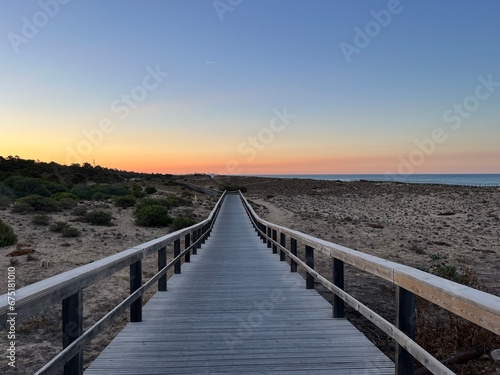 Boardwalk to the ocean  orange horizon  blue pure sky  no people