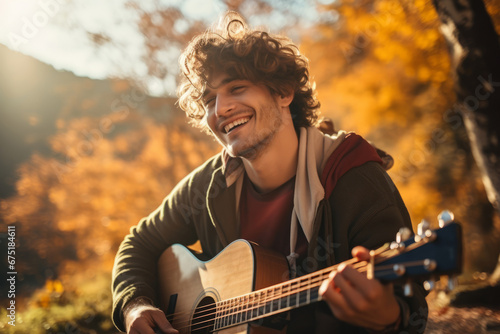 Cheerful young male musician is performing song outdoors, autumn season