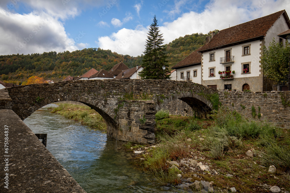 Old medieval stone bridge over the Anduña river in the typical Pyrenean village of Ochagavía in Navarra, Spain with midday light