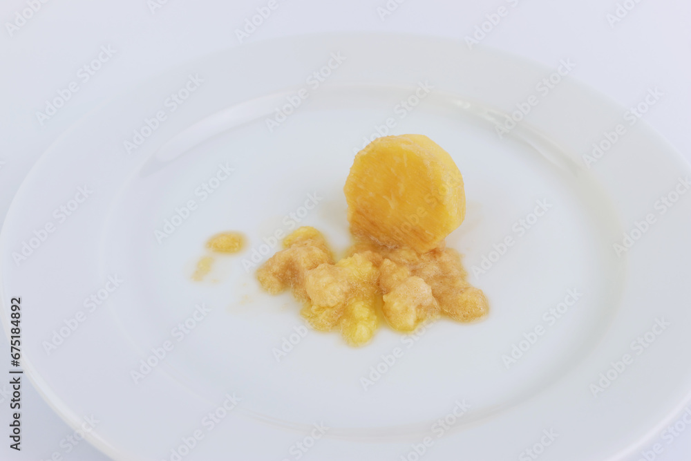 A miniature grater and grated potatoes on a white plate.