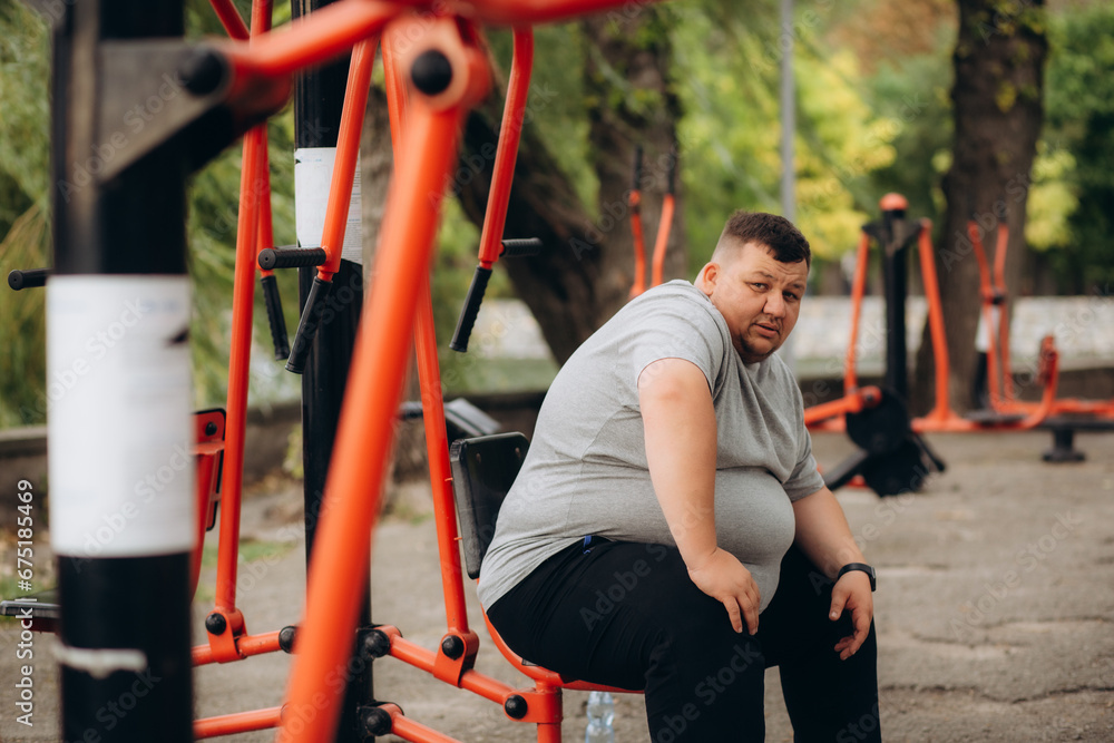 a fat man in the park is doing sports to lose weight