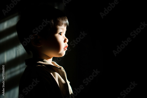 a young boy standing in the dark with a shadow on the wall photo