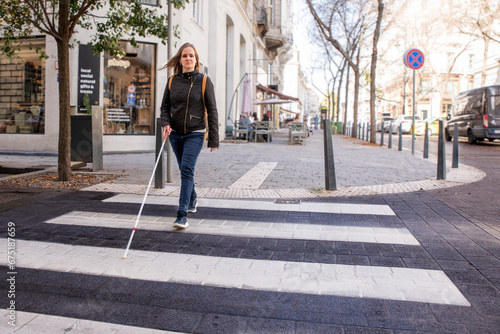 Φωτογραφία Visually impaired woman with white cane in hand walking through pedestrian cross