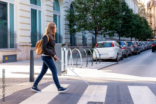Foto Visually impaired woman with white cane in hand walking through pedestrian cross