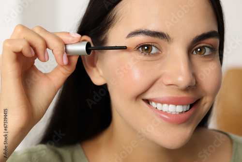 Beautiful woman applying serum onto her eyelashes, closeup. Cosmetic product photo
