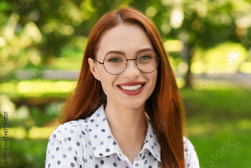Portrait of happy young woman with glasses outdoors. Lady with beautiful smile looking into camera
