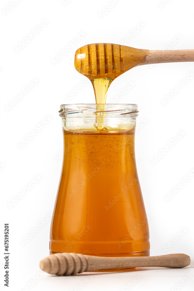 Honey drips from a spoon into a jar on white background Honey drips from a spoon into a jar on white background