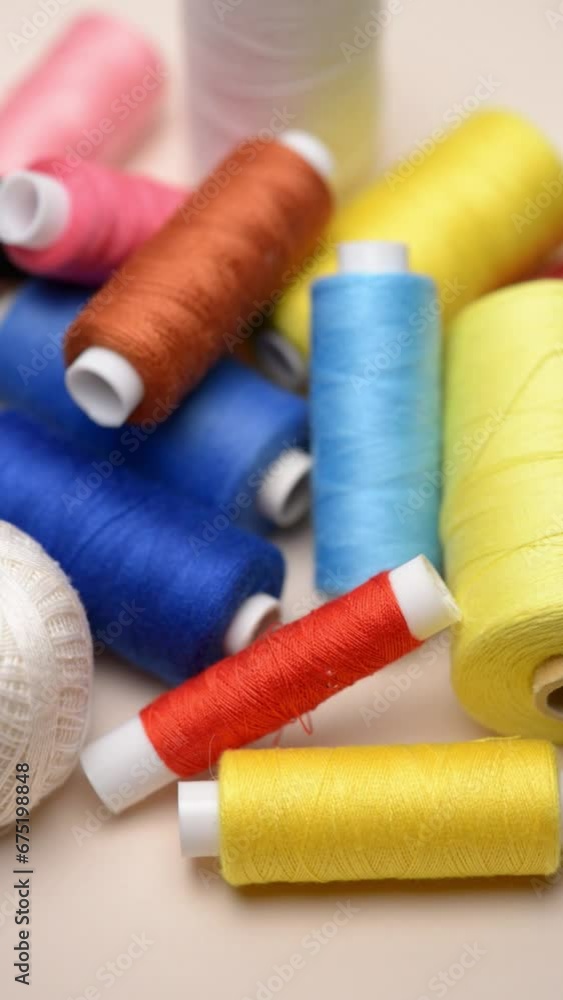 Heap of colorful spools with thread and needle for sewing, rotating motion, vertical video
