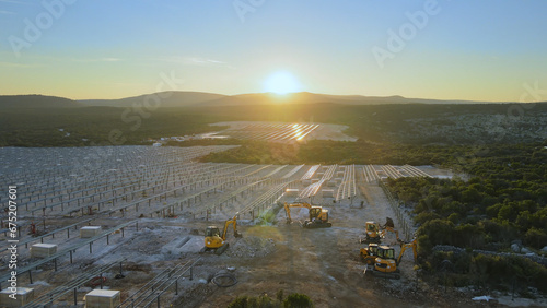 Photography Aerial view over machinery at a solar farm construction site, during sunset