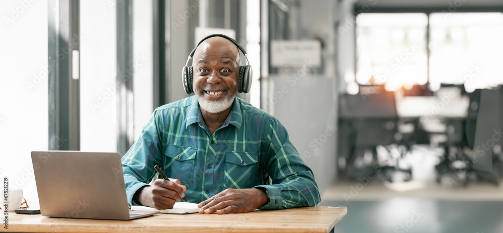 portrait of happy bald and bearded african american senior man wearing headphones, enjoying working at home office. - obrazy, fototapety, plakaty 