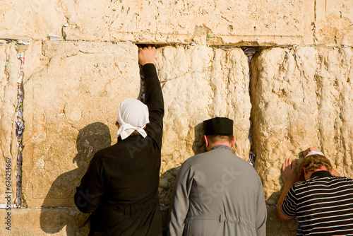 Praying Jewish people, traditional Orthodox Jews, in front of the Wester Wall, Wailing Wall, Jerusalem, Israel. Putting small paper pieces of prayer in cracks of the wall. 