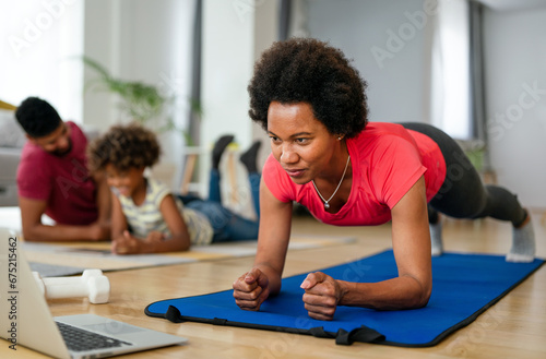 Happy african american fit woman working out with online traning at home. Sport technology concept
