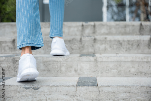 With determination, a woman in sneakers takes on the city stairs, reflecting her relentless progress. Every step symbolizes her commitment to success and ongoing growth. step up photo