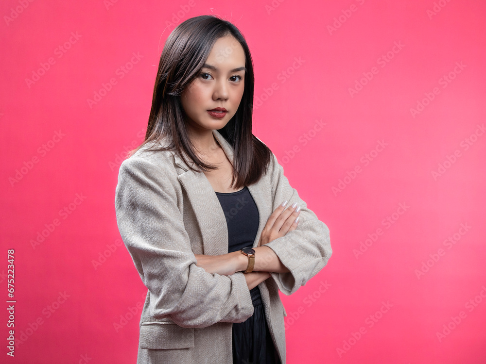 A portrait of an Indonesian Asian woman wearing a cream-colored blazer, posing happily. Isolated against a magenta background. A portrait of an Indonesian Asian woman wearing a cream-colored blazer, posing happily. Isolated against a magenta background.