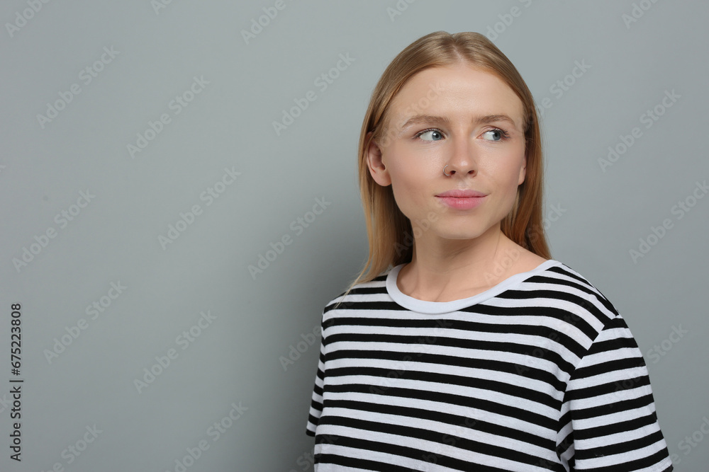 Portrait of beautiful young woman in striped t-shirt on grey background. Space for text Portrait of beautiful young woman in striped t-shirt on grey background. Space for text
