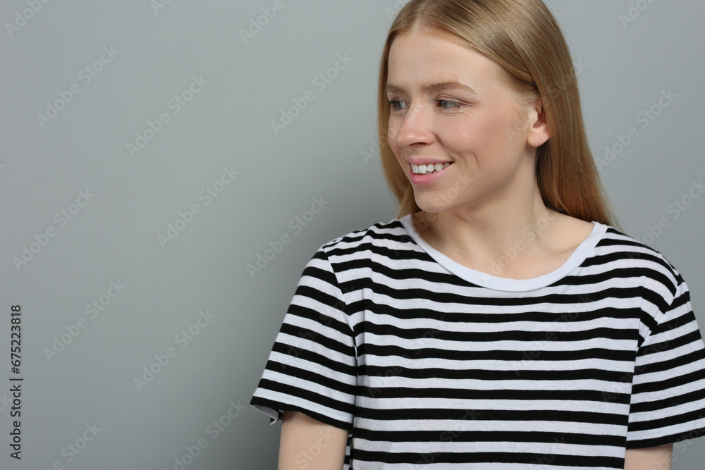 Portrait of beautiful young woman in striped t-shirt on grey background. Space for text Portrait of beautiful young woman in striped t-shirt on grey background. Space for text