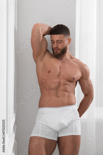 Young man in stylish underwear near white wall indoors