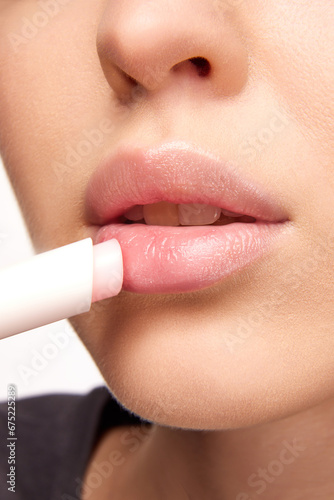 Perfect natural lip makeup. Close up photo of woman applying hygienic lip balm. Moisturizing chap stick for dry lips.