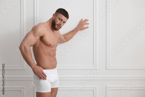 Young man in stylish underwear near white wall indoors. Space for text © New Africa