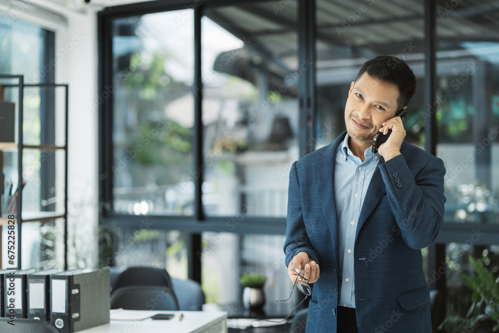 Smiling Asian young freelancer working from home remotely.He is talking on the phone. Smiling Asian young freelancer working from home remotely.He is talking on the phone.