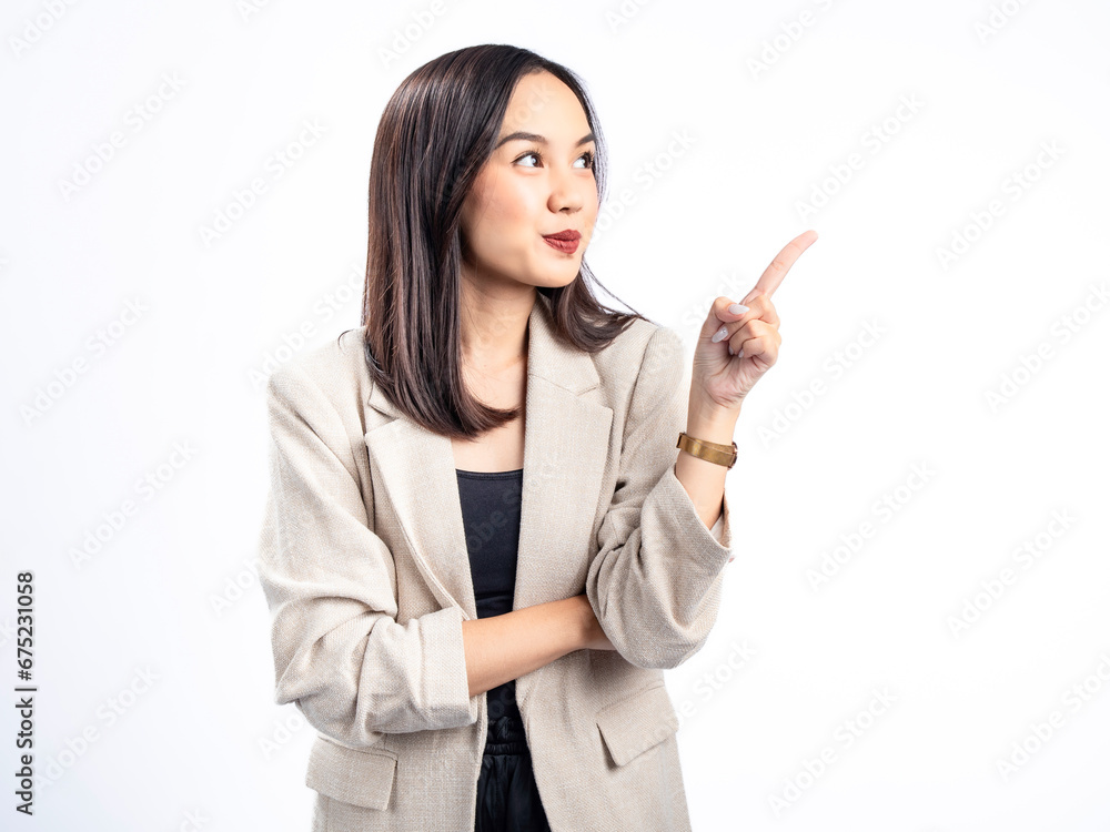 A portrait of an Indonesian Asian woman wearing a cream-colored blazer, posing as if having an idea with her index finger pointing upward. Isolated against a white background. A portrait of an Indonesian Asian woman wearing a cream-colored blazer, posing as if having an idea with her index finger pointing upward. Isolated against a white background.