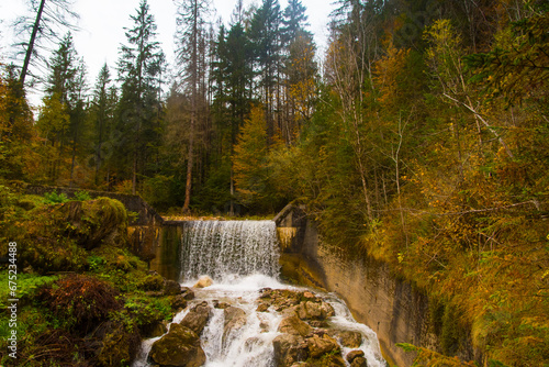 La cascata di un ruscello in un bosco colorato dal foliage autunnale sulle Dolomiti bellunesi photo