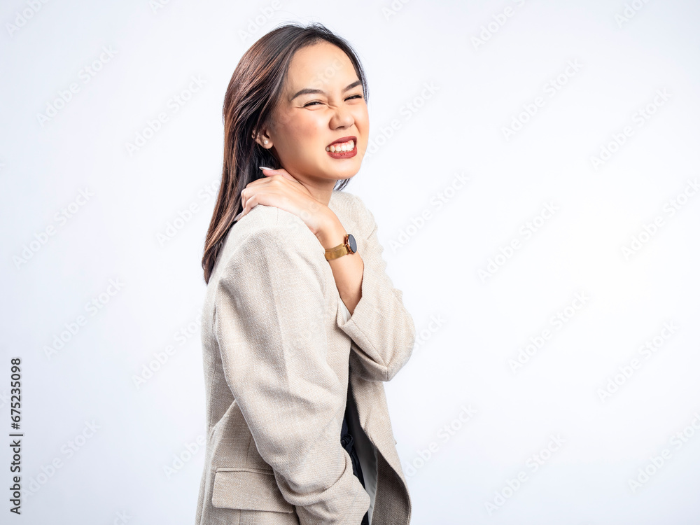 A portrait of an Indonesian Asian woman wearing a cream-colored blazer, posing with a tired body and holding her shoulders. Isolated against a white background. A portrait of an Indonesian Asian woman wearing a cream-colored blazer, posing with a tired body and holding her shoulders. Isolated against a white background.