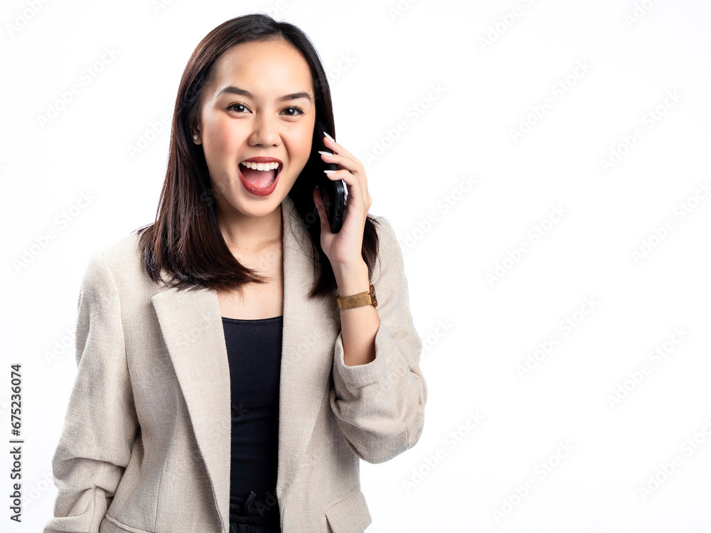 A portrait of an Indonesian Asian woman wearing a cream-colored blazer, talking on the phone. Isolated against a white background. A portrait of an Indonesian Asian woman wearing a cream-colored blazer, talking on the phone. Isolated against a white background.
