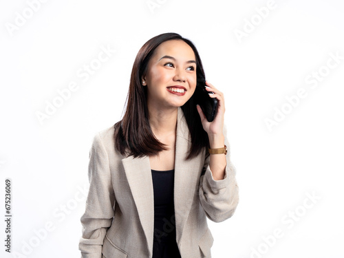 A portrait of an Indonesian Asian woman wearing a cream-colored blazer, talking on the phone. Isolated against a white background.