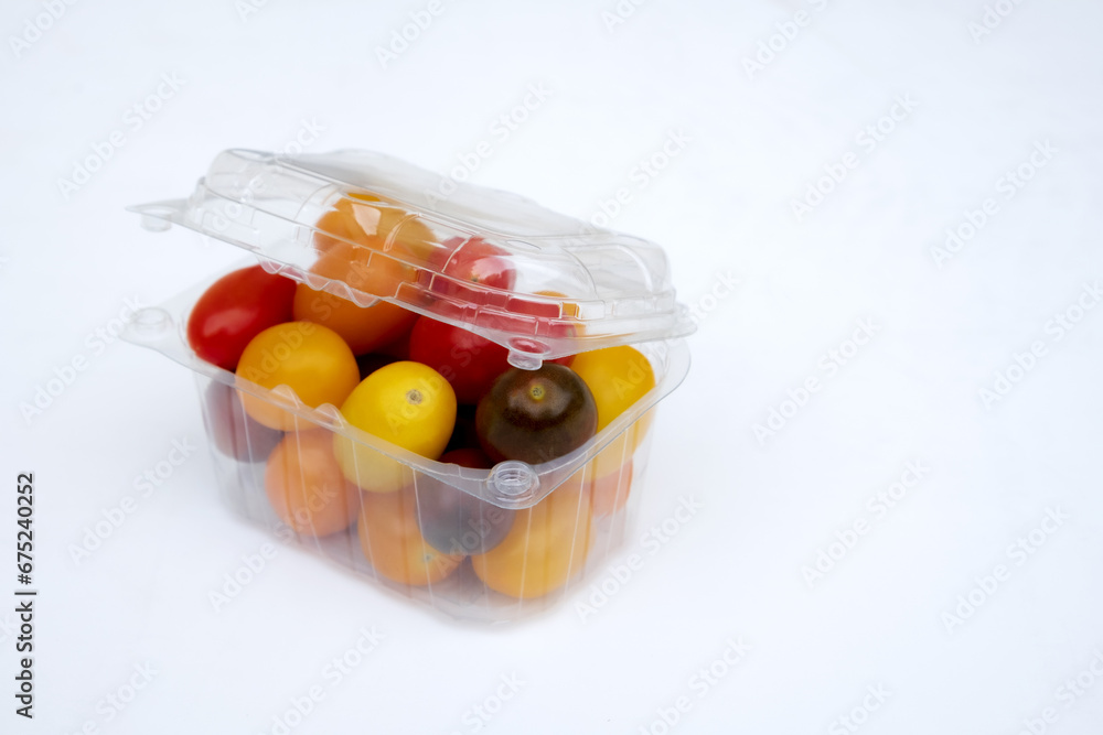 Containers plastic transparency with, Different sorts of tomatoes isolated on white background. Fresh, ripe type of small and round cocktail tomatoes, of red, yellow and orange color. Containers plastic transparency with, Different sorts of tomatoes isolated on white background. Fresh, ripe type of small and round cocktail tomatoes, of red, yellow and orange color.