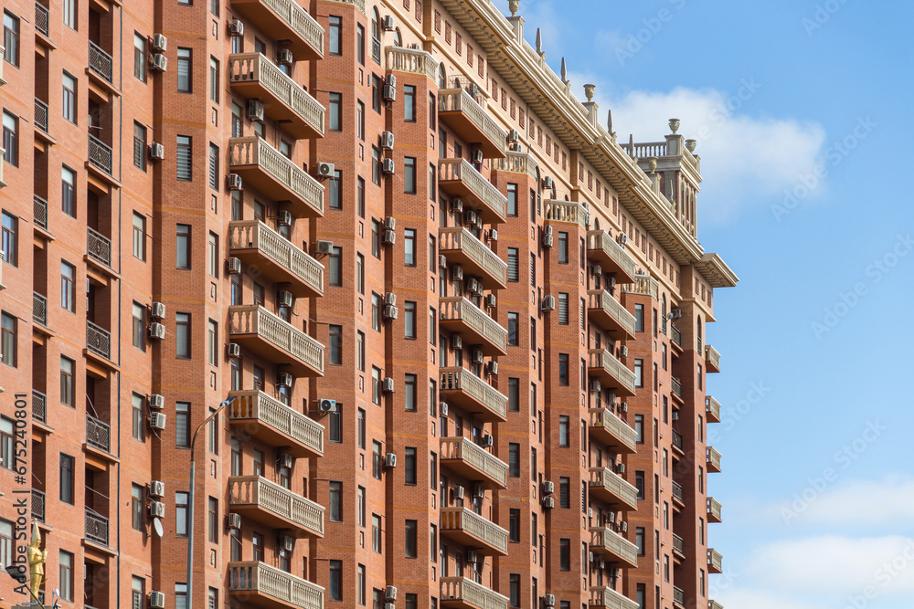 Fototapeta premium Facade of a beautiful residential complex in Kazakhstan. Balustrade on the roof of a multi-storey building. Balconies with balusters on the house.