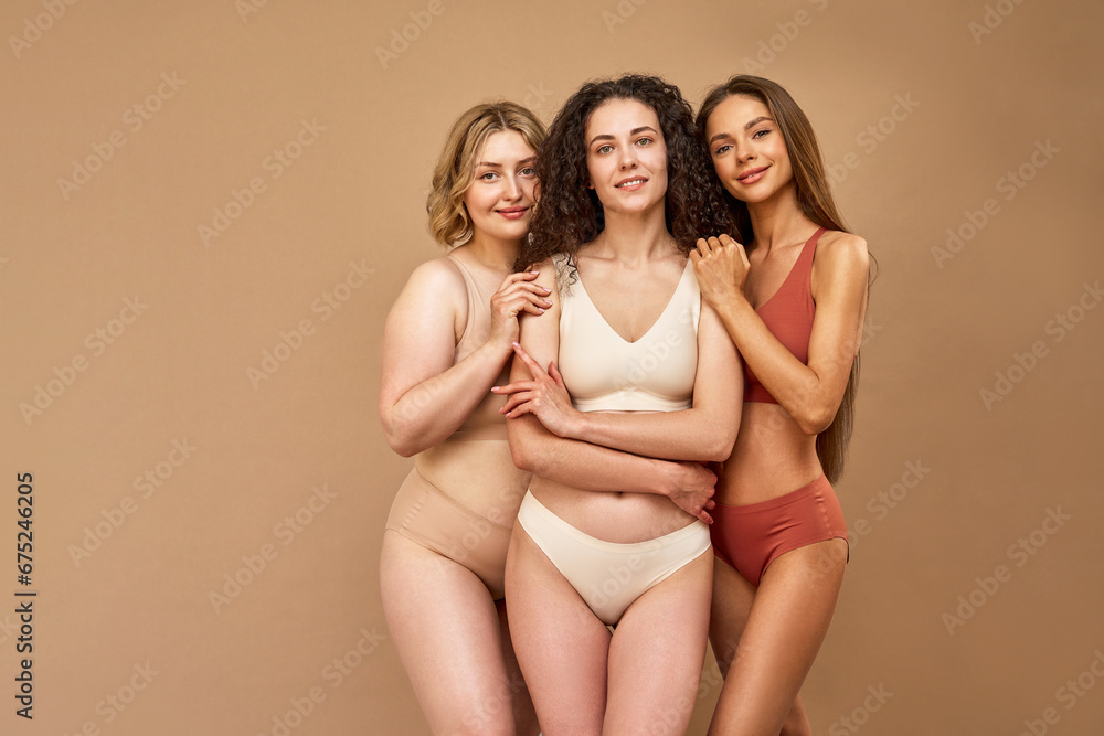 © Velista production - Feminine beauty. Group of three beautiful caucasian women with different body types and skin color standing in embrace in studio. Young ladies wearing lingerie posing over beige background. © Velista production - Feminine beauty. Group of three beautiful caucasian women with different body types and skin color standing in embrace in studio. Young ladies wearing lingerie posing over beige background.