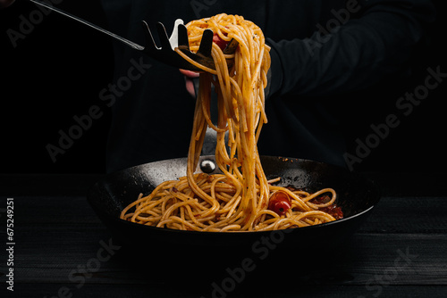 A man prepares pasta with spaghetti, tomatoes and spices.