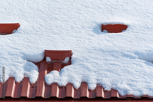 Roof made of brown metal tiles covered with snow. Snow guard system. Ice and snow retention.