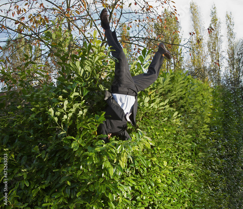 Businessman landing in a hedge upside down
